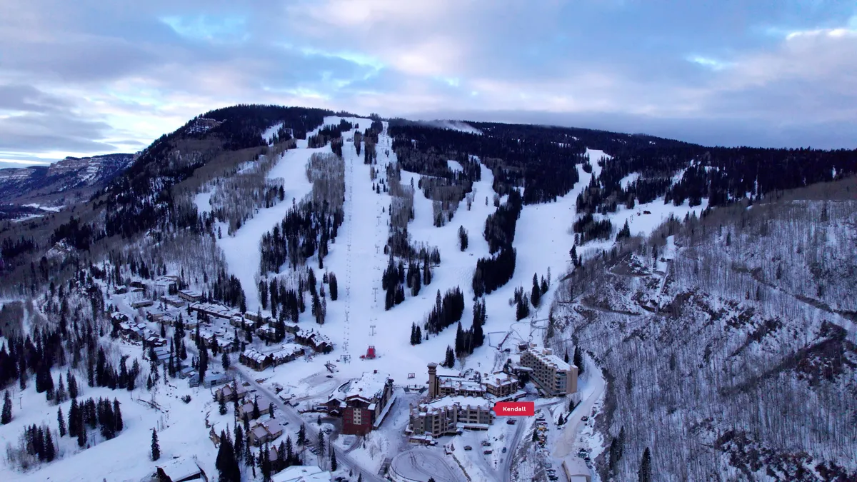 A sweeping view of snow-covered slopes with prominent ski lifts, a mountainous backdrop, and inviting lodging facilities nestled at the base. The image captures both the adventure of skiing and the serene alpine atmosphere.