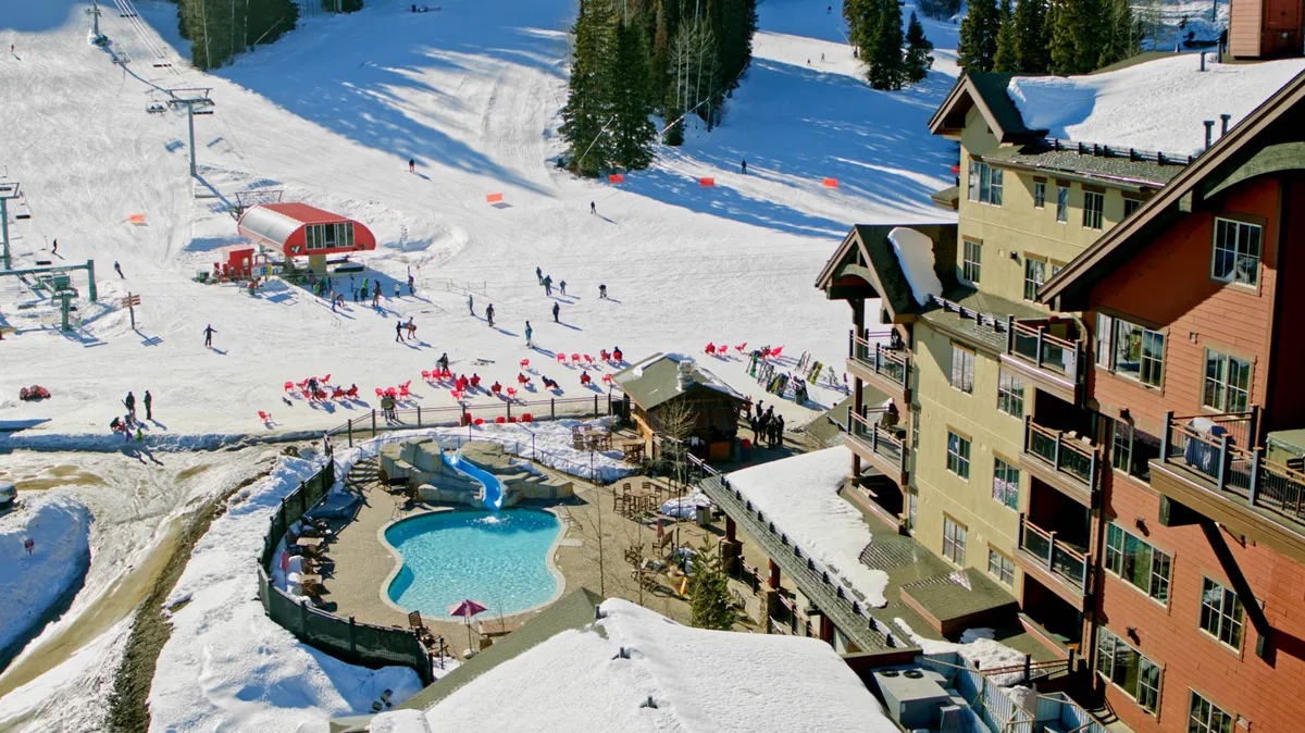 A vibrant exterior shot featuring ski slopes, a swimming pool, a ski lift, the hotel building, and an outdoor seating area. The scene is lively and joyful, capturing both winter and après-ski relaxation.