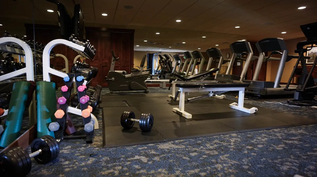 This image captures a well-equipped fitness center featuring dumbbells, treadmills, a weight bench, and exercise mats. The space is bright, open, and inviting, offering multiple workout options for strength training, cardio, and group fitness activities. The overall mood is motivational, reflecting a place where residents can recharge and maintain their well-being.